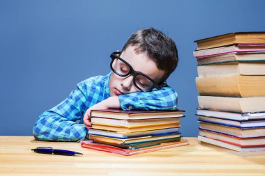 kitap yığını üzerinde uyuyan çocuk