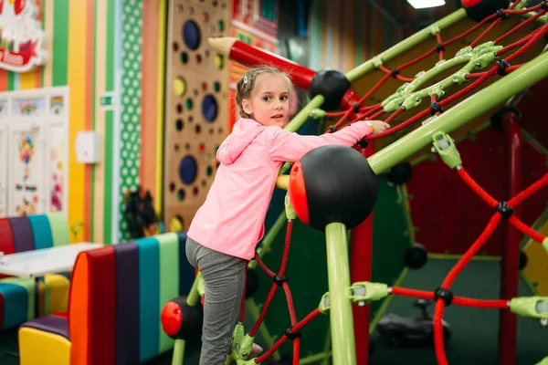 Liten flicka klättring på rep på lekplats — Stockfoto