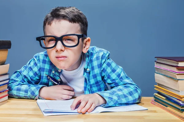 Colegial en el escritorio con muchos libros — Foto de Stock