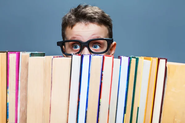 Schooljongen gluren achter boeken — Stockfoto