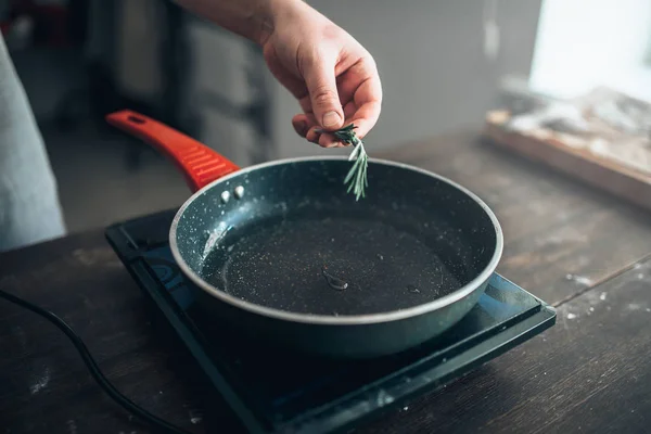 Chef poniendo romero a la sartén — Foto de Stock