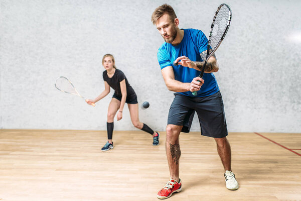 man and woman playing squash 