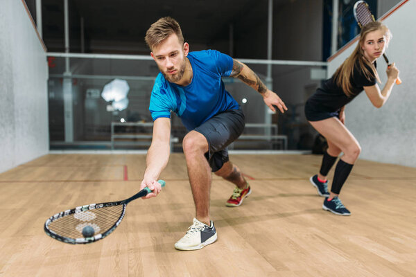 man and woman playing squash 