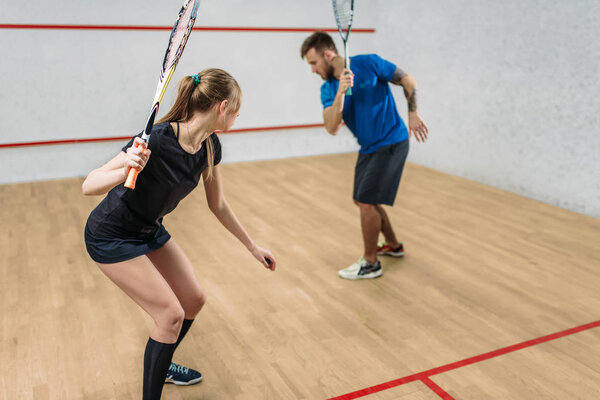 man and woman playing squash 