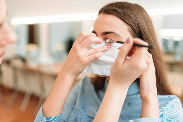 make up artist putting mascara on eyelashes