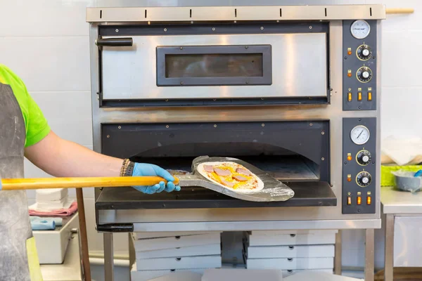 Att sätta raw pizza i ugn — Stockfoto