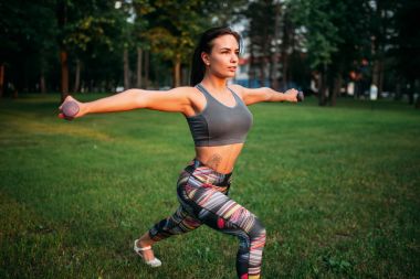 Dambıllarla egzersiz yapan kadın.