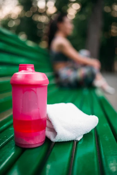 Бутылка спортивной воды и полотенце на скамейке — стоковое фото