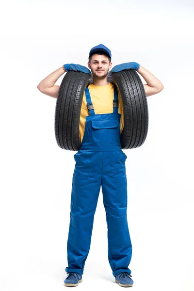 Reparador em uniforme azul com pneus — Fotografia de Stock