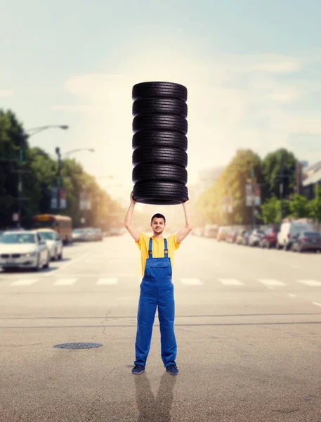 Riparatore che tiene una pila di pneumatici — Foto Stock