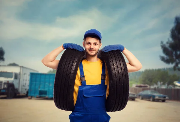 Reparador em uniforme azul com pneus — Fotografia de Stock