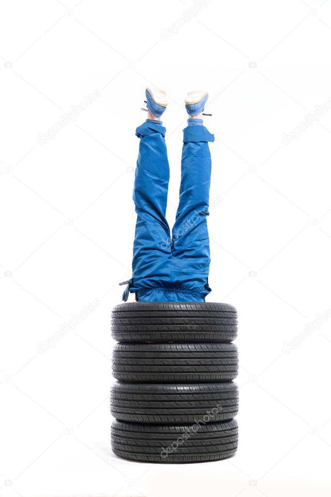 legs of worker sticking out of pile of tires