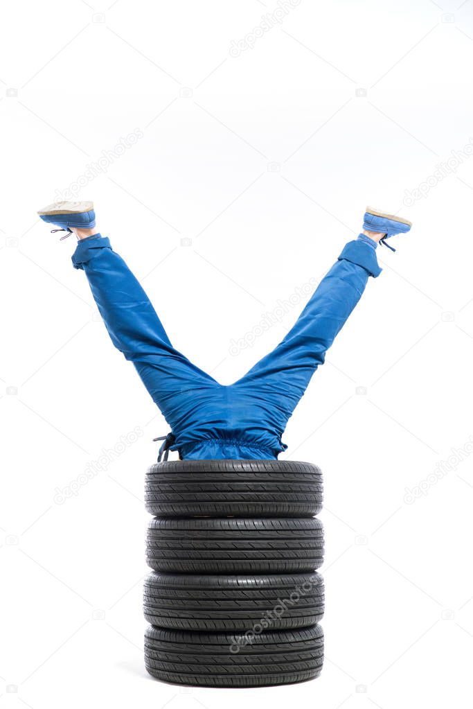 legs of worker sticking out of pile of tires