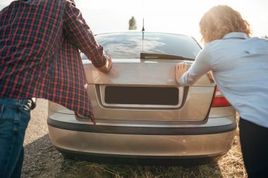 erkek ve kadın kırık araba itme