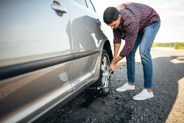 Man försöker byta fälg av bil — Stockfoto