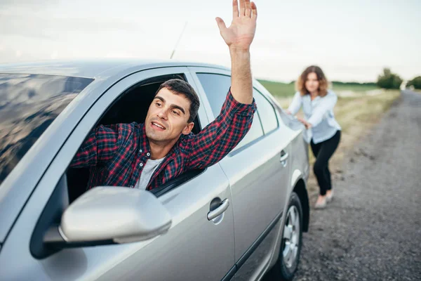 Hombre conduciendo y mujer empujando coche — Foto de Stock