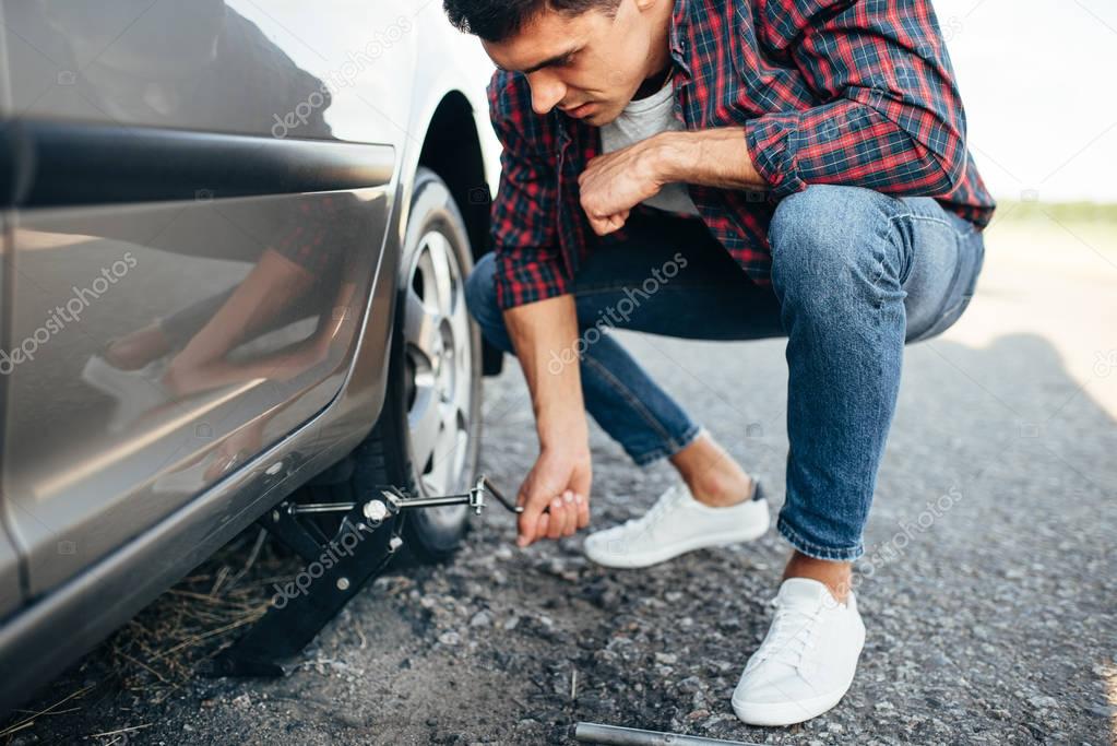 man trying to replace wheel of car