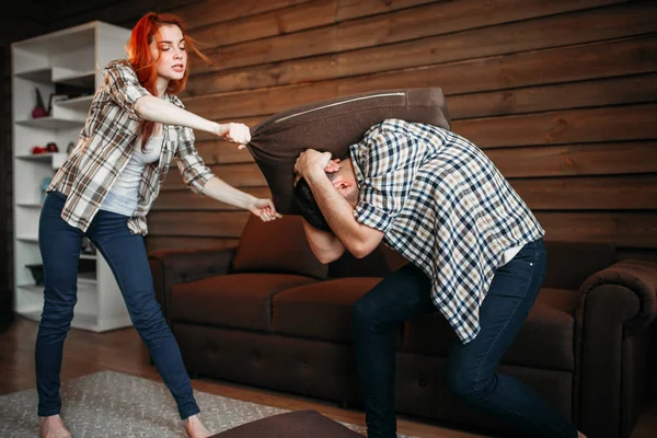Woman beating man with pillow — Stock Photo, Image