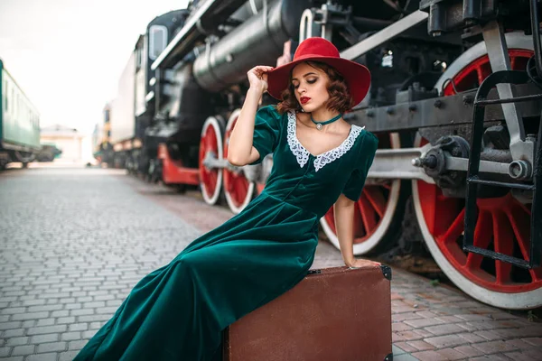 Kobieta siedzi na pociąg parowy agaisnt walizka — Zdjęcie stockowe