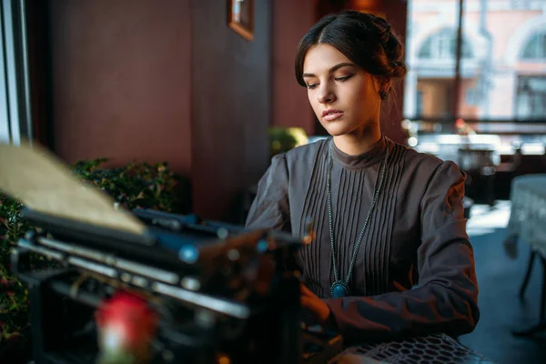 Jeune femme avec machine à écrire antique — Photo