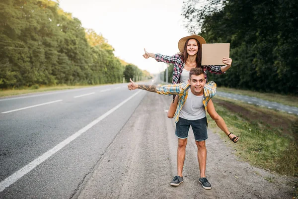 Hitchhiking couple with empty cardboard — Stock Photo, Image