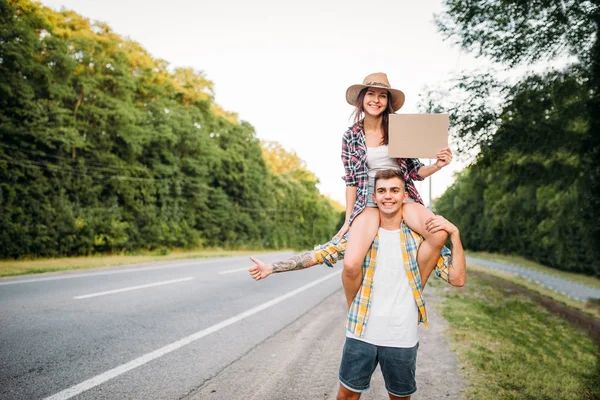 Hitchhiking couple with empty cardboard — Stock Photo, Image