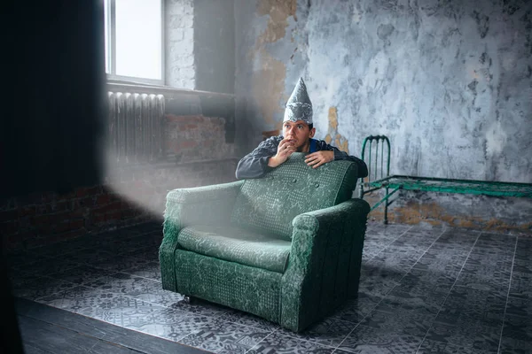 Hombre en casco de aluminio viendo la televisión —  Fotos de Stock