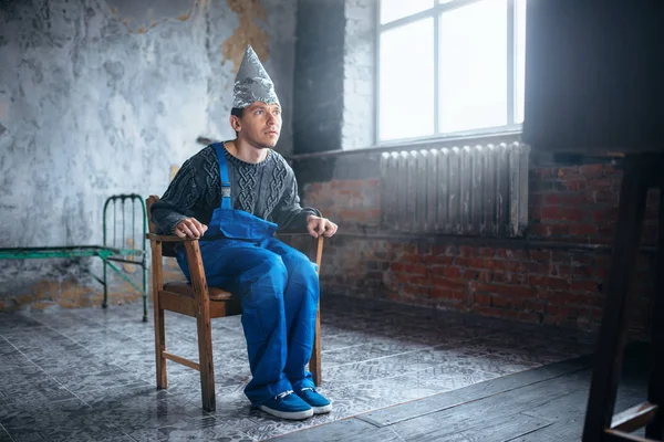 Hombre en casco de aluminio viendo la televisión — Foto de Stock