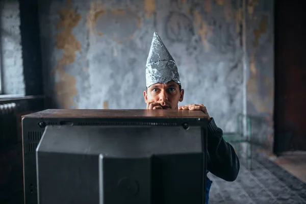 Hombre en casco de aluminio viendo la televisión —  Fotos de Stock