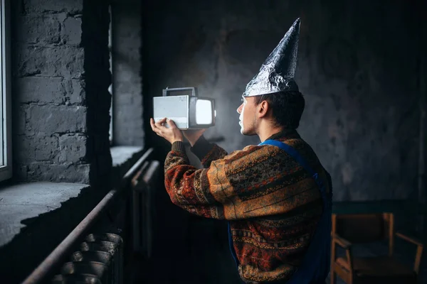 Hombre en casco de aluminio viendo la televisión — Foto de Stock