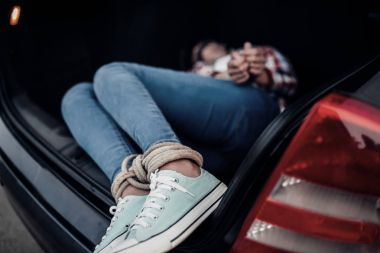 female victim of maniac in car trunk, legs and hands stringed with rope. Horror, kidnapping concept clipart