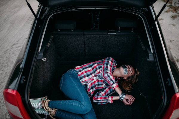 Жертва маньяка в багажнике, рот и руки заклеены изолентой. Ужас, концепция похищения
