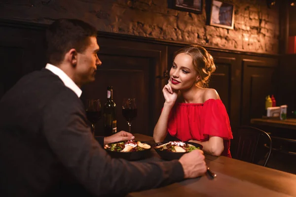 若い愛カップルのレストランでロマンチックな日付 赤いドレスとハンサムな男がダイニングで優雅な女性 — ストック写真
