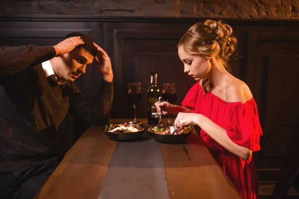 年轻夫妇在餐馆吵架 糟糕的浪漫约会 典雅的妇女在红色礼服和英俊的人用餐 — 图库照片