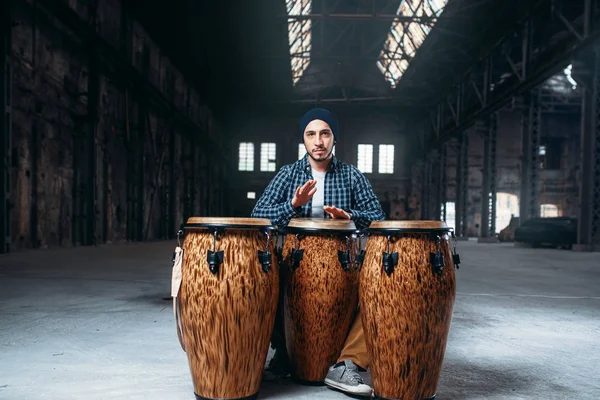 若い男性ドラマー再生アフリカ木製ドラム 背景に工場出荷時の肖像画 ジャンベ パーカッション楽器 — ストック写真