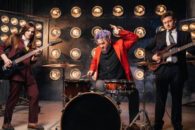 müzisyenler sahne ışıkları, retro tarzı, gitaristler ve davulcu, rock grubu ile takım elbiseli