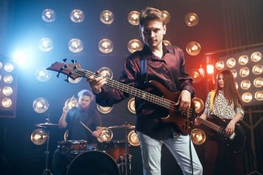 arka plan ışığı ile bas gitar, rock grubu, sahne alanı üzerinde oynarken gitarist