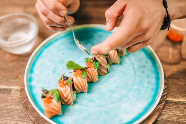 男厨师在蓝色盘子上装饰寿司卷 传统日本料理 — 图库照片