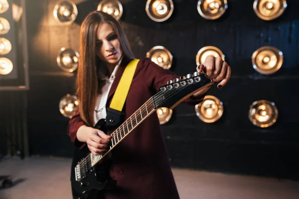 背景のライト Bas ギター ロック バンド ステージ上でプレイ女性ギタリスト — ストック写真
