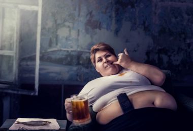 Obezite ve sağlıksız yaşam tarzı kavramı TV izlerken, bira, bulimik, içme koltukta oturan kadın kilolu