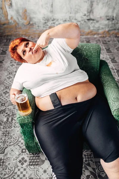 坐在扶手椅上的超重妇女 看电视和喝啤酒 肥胖和不健康的生活方式概念 — 图库照片