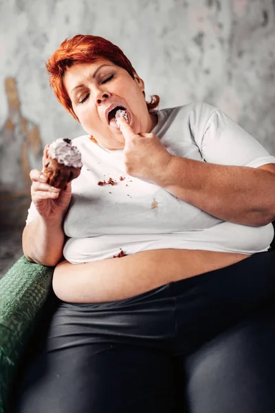 Υπέρβαρα Γυναίκα Κάθεται Στην Πολυθρόνα Και Τρώει Γλυκά Cupcake Τεμπελιά — Φωτογραφία Αρχείου