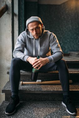 şişe alkol ve beyzbol sopası kurban için suç kavramı bekleyen merdivenlerde oturan erkek hırsız