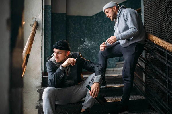 两个男劫匪在楼梯上 街头强盗与酒瓶等待受害者 犯罪概念 — 图库照片