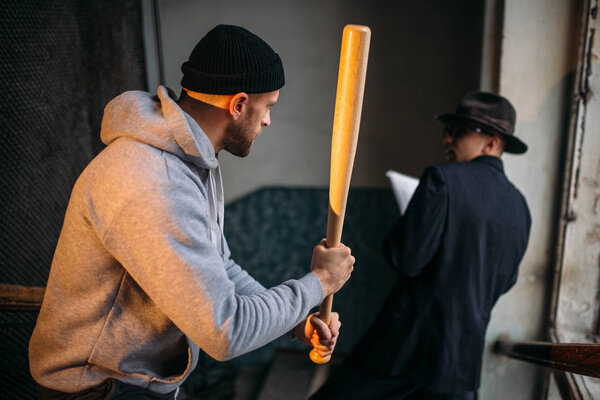 robber with  baseball bat  attacking victim in the entrance, crime concept