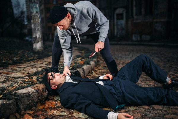 thief killing victim with knife on night street, crime concept