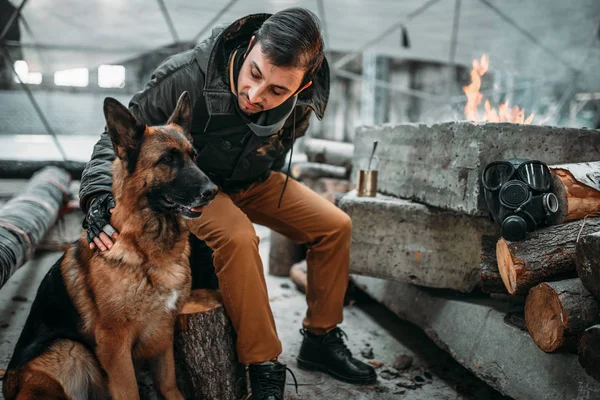 stalker, post-apocalypse soldier feeding dog. Post apocalyptic lifestyle on ruins, doomsday concept
