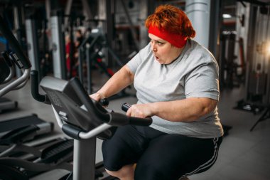 şişman Terli kadın spor salonunda egzersiz bisikleti makinesi kullanma