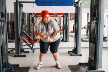 şişman Terli kadın spor salonunda egzersiz makinesi kullanma