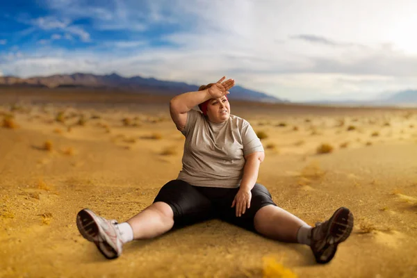 疲倦的肥胖妇女在活跃训练以后坐在沙漠谷 — 图库照片